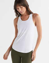 Woman wearing a white tank top and green leggings on a white background