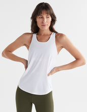 Woman wearing a white tank top and green leggings on a white background