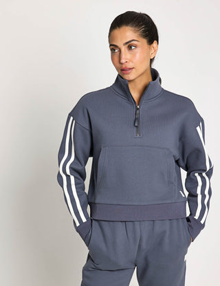 Person wearing a gray tracksuit with white stripes on a light gray background