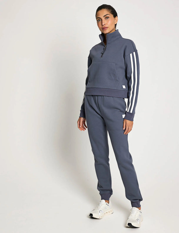 Woman wearing a grey tracksuit with white stripes on a white background