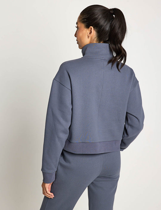 Person wearing a gray tracksuit against a plain background
