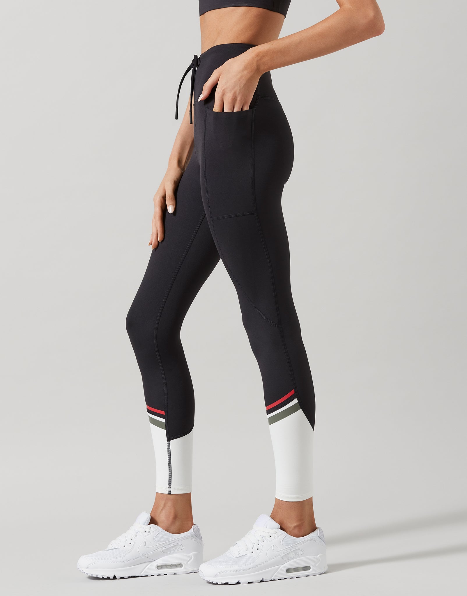 Woman wearing black activewear leggings with white accents on a gray background