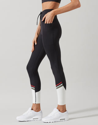 Woman wearing black activewear leggings with white accents on a gray background