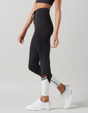 Person wearing black leggings with a white stripe on a gray background