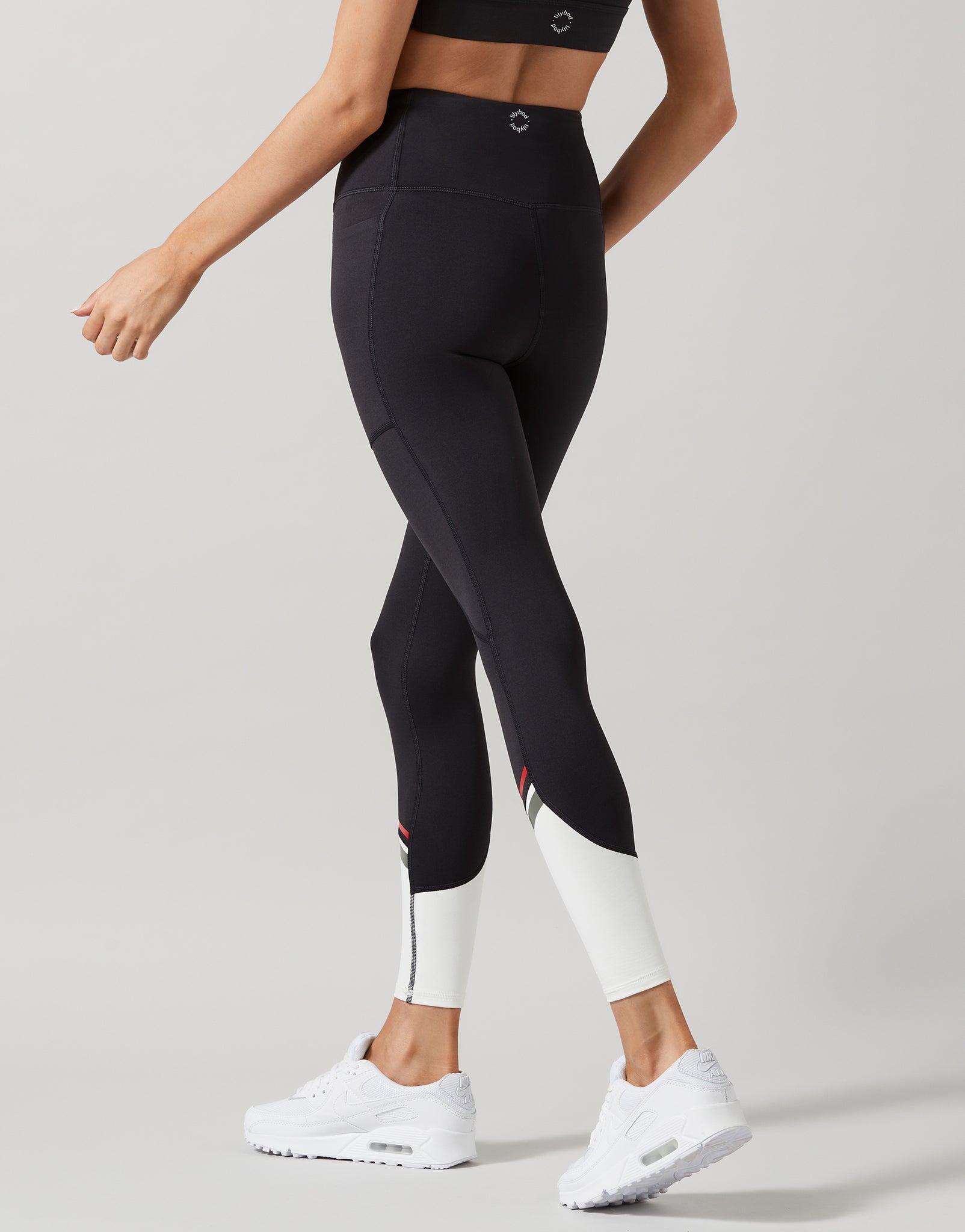 Person wearing black leggings with white accents on a gray background