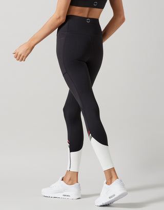 Person wearing black leggings with white accents on a gray background