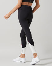 Person wearing black leggings with white accents on a gray background