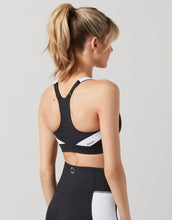 Woman wearing a black sports bra with a visible brand logo on a light gray background