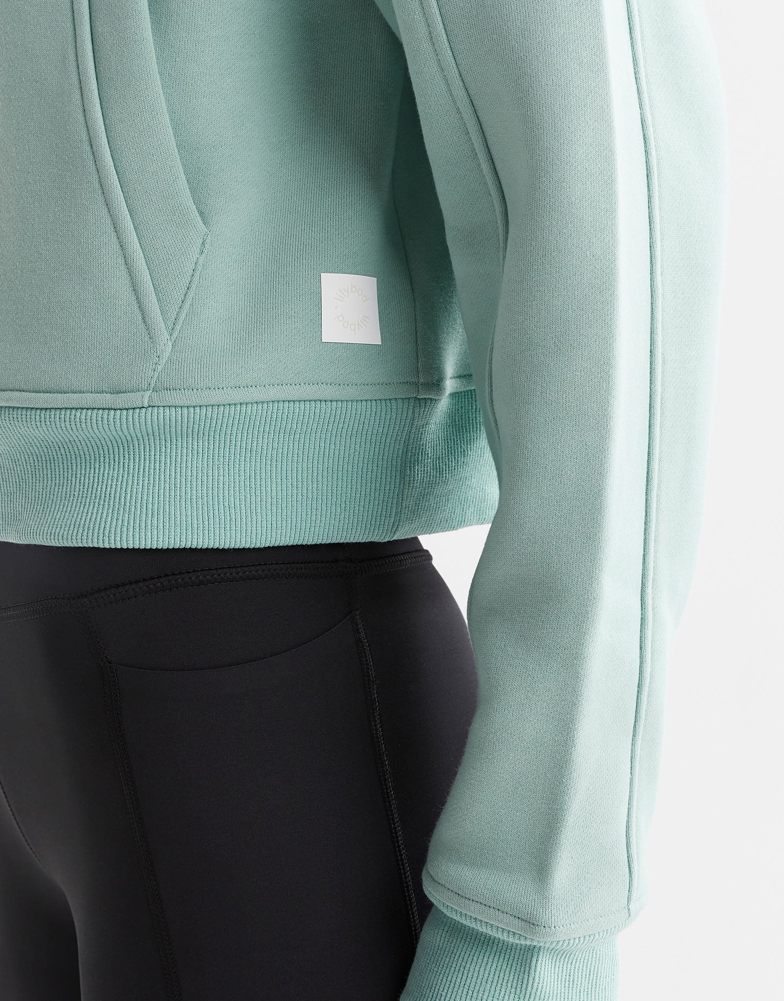 Close up of a green sweater and black leggings.