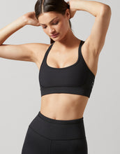 Woman wearing a black sports bra and leggings on a gray background