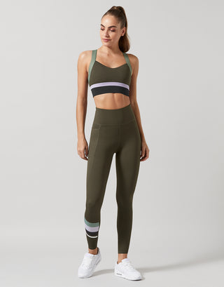 Woman wearing an olive green athletic outfit on a light gray background