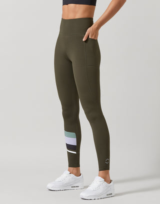 A woman wearing olive green leggings and white sneakers.