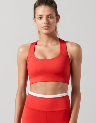 A woman wearing a red sports bra and leggings.