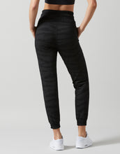 Person wearing black Lilybod Rylee jogger pants on a gray background
