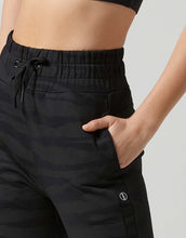 Black athletic pants worn by a person on a plain background