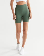 Person wearing green high-waisted shorts on a white background