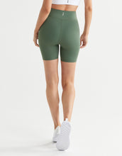 Person wearing green high-waisted shorts on a white background