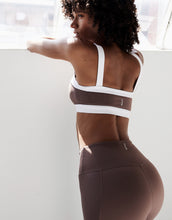 A woman wearinga a brown athletic set looking out a window
