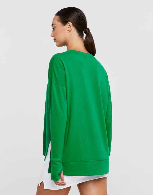 Woman wearing a green sweatshirt and white skirt with a white background