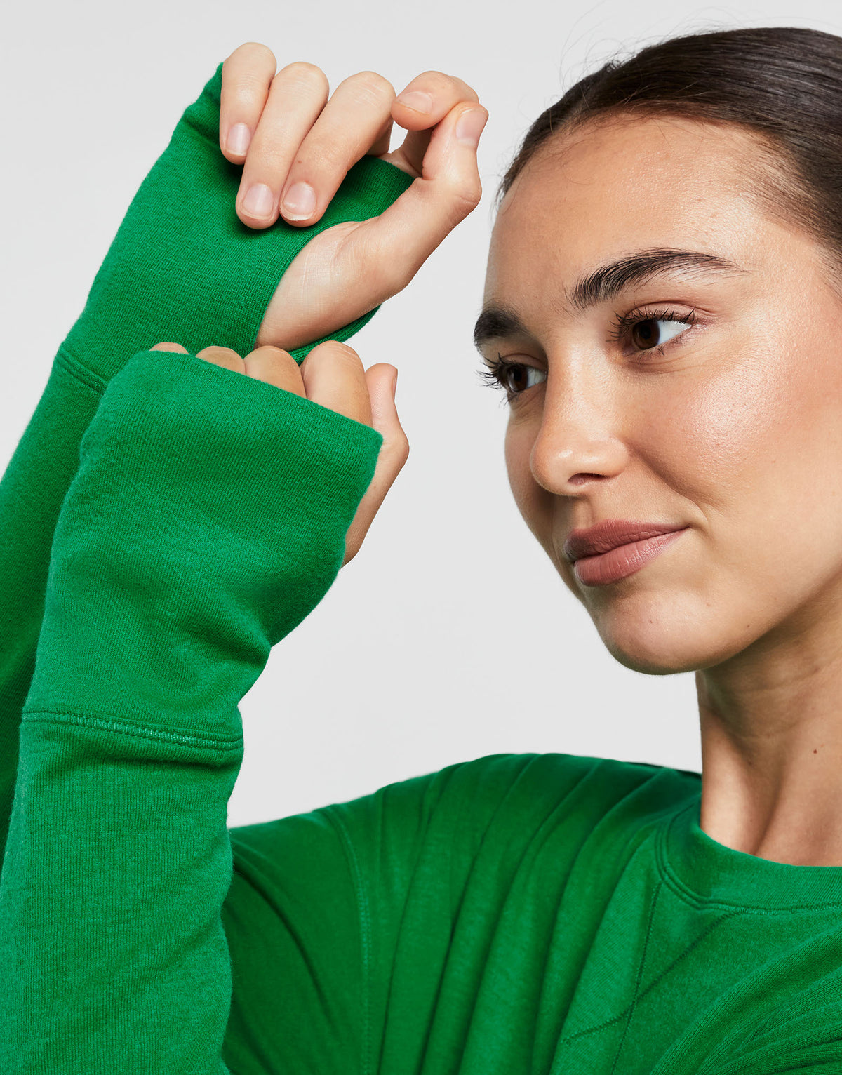 Close up of a woman wearing a green sweater against a plain background