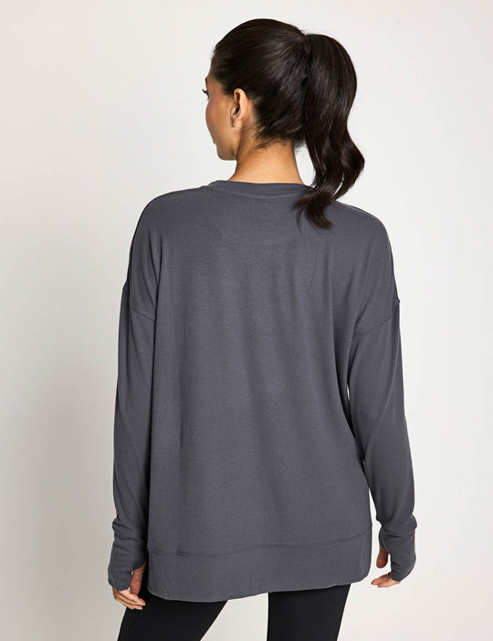 Person wearing a gray long-sleeve top from behind on a plain background