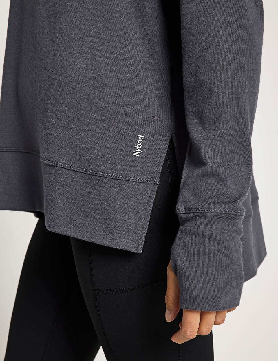 Dark gray sweatshirt close up of sleeve with a brand logo on a white background