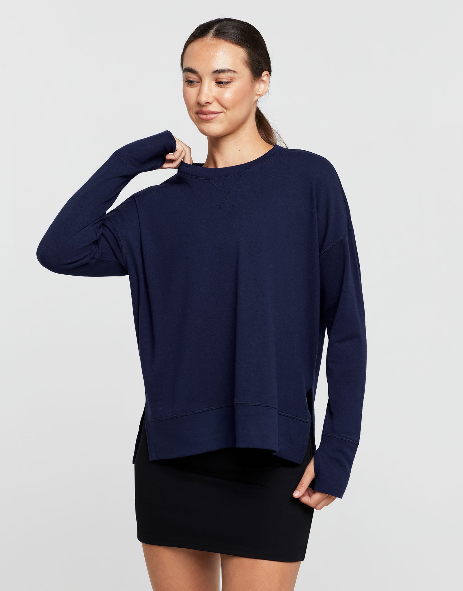 Woman wearing a navy blue sweater over a black skirt on a white background