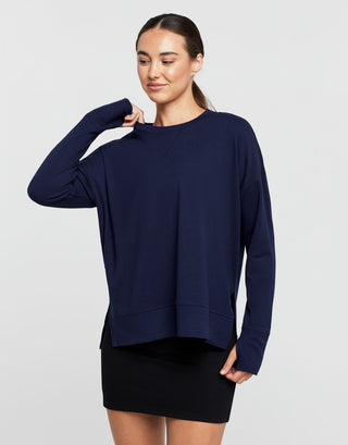 Woman wearing a navy blue sweater over a black skirt on a white background