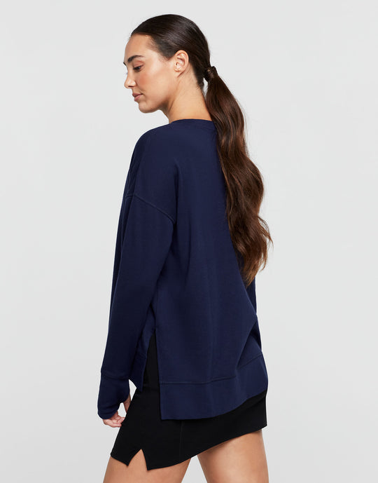 Woman wearing a navy blue oversized sweatshirt on a light gray background
