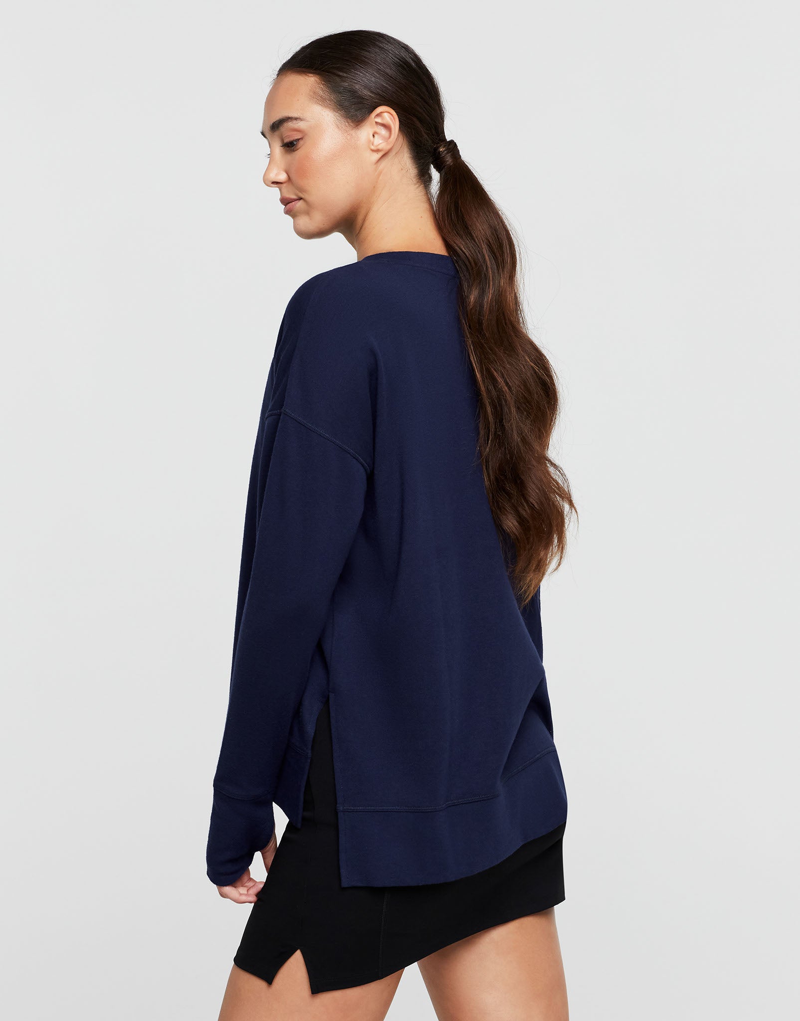 Woman wearing a navy blue oversized sweatshirt on a light gray background