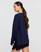 Woman wearing a navy blue oversized sweatshirt on a light gray background