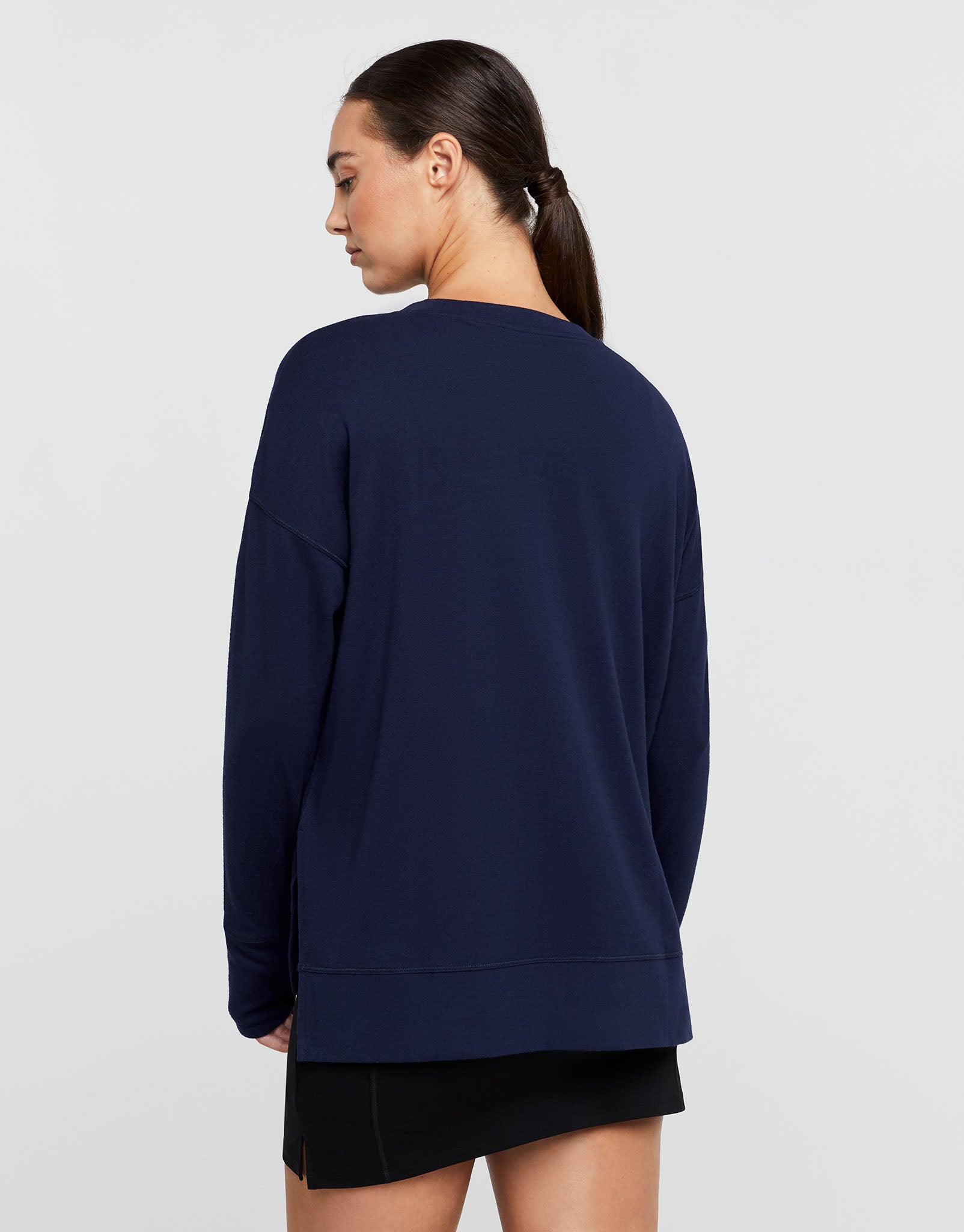 Woman wearing a navy blue sweatshirt on a light gray background