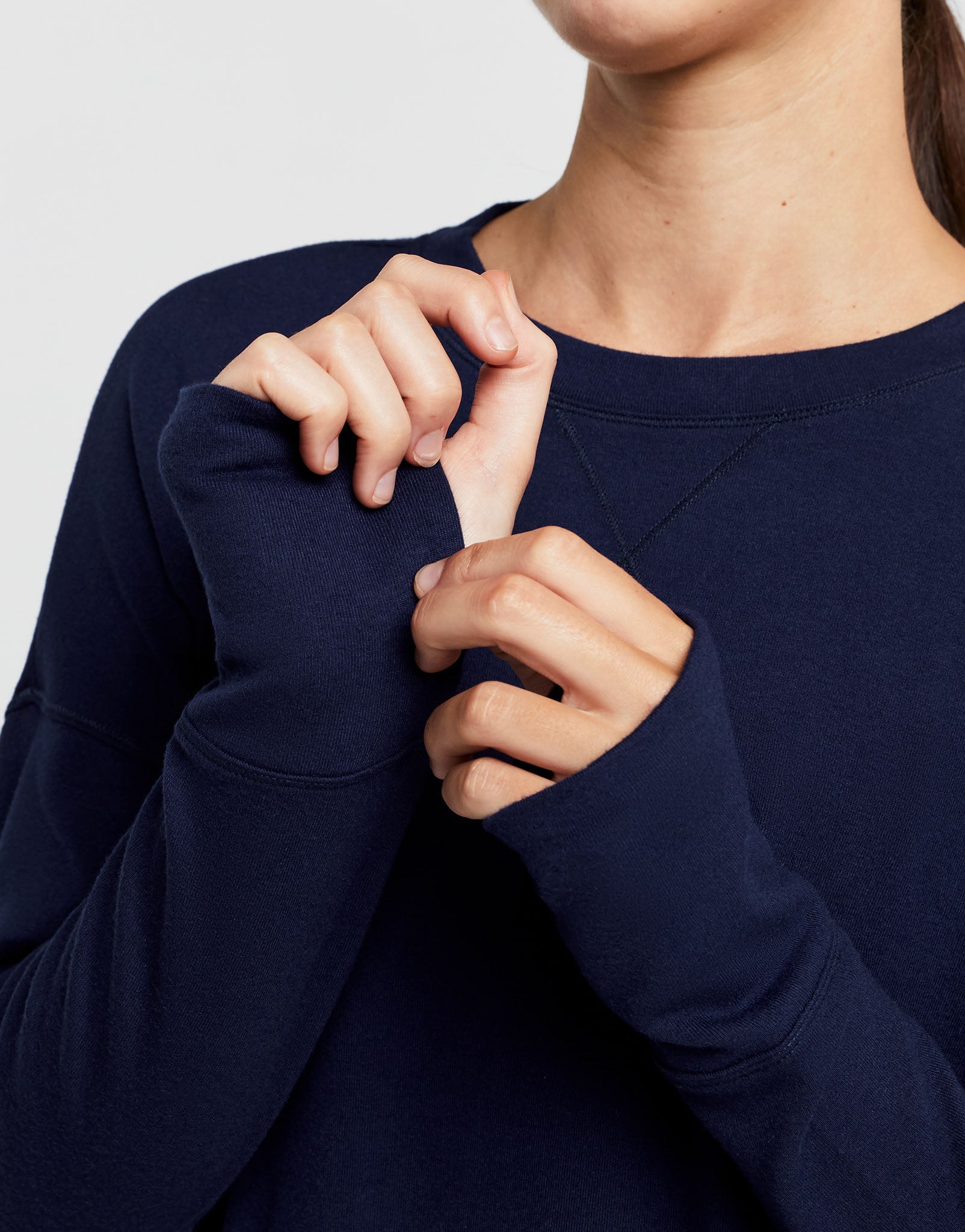 Close up of a woman wearing a navy blue sweater with a plain background