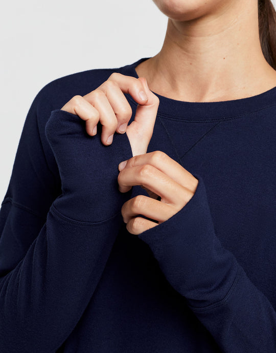 Close up of a woman wearing a navy blue sweater with a plain background