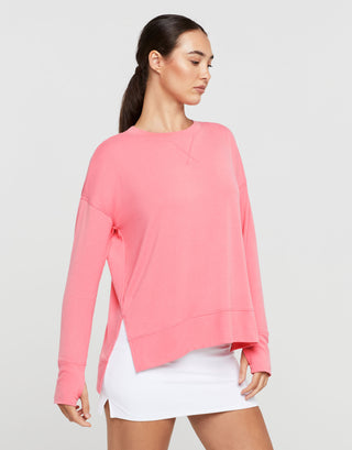 Woman wearing a pink long-sleeve top and white shorts on a light gray background