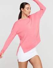 Woman wearing a pink long-sleeve top and white shorts on a light gray background