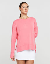 Woman wearing a pink long-sleeve top and white shorts on a light gray background