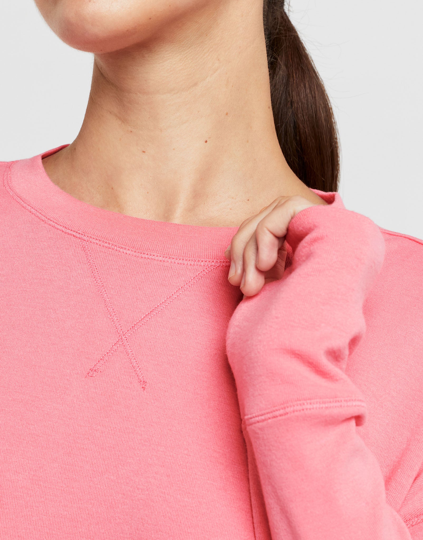 Close-up of a person wearing a pink sweatshirt with a blurred background