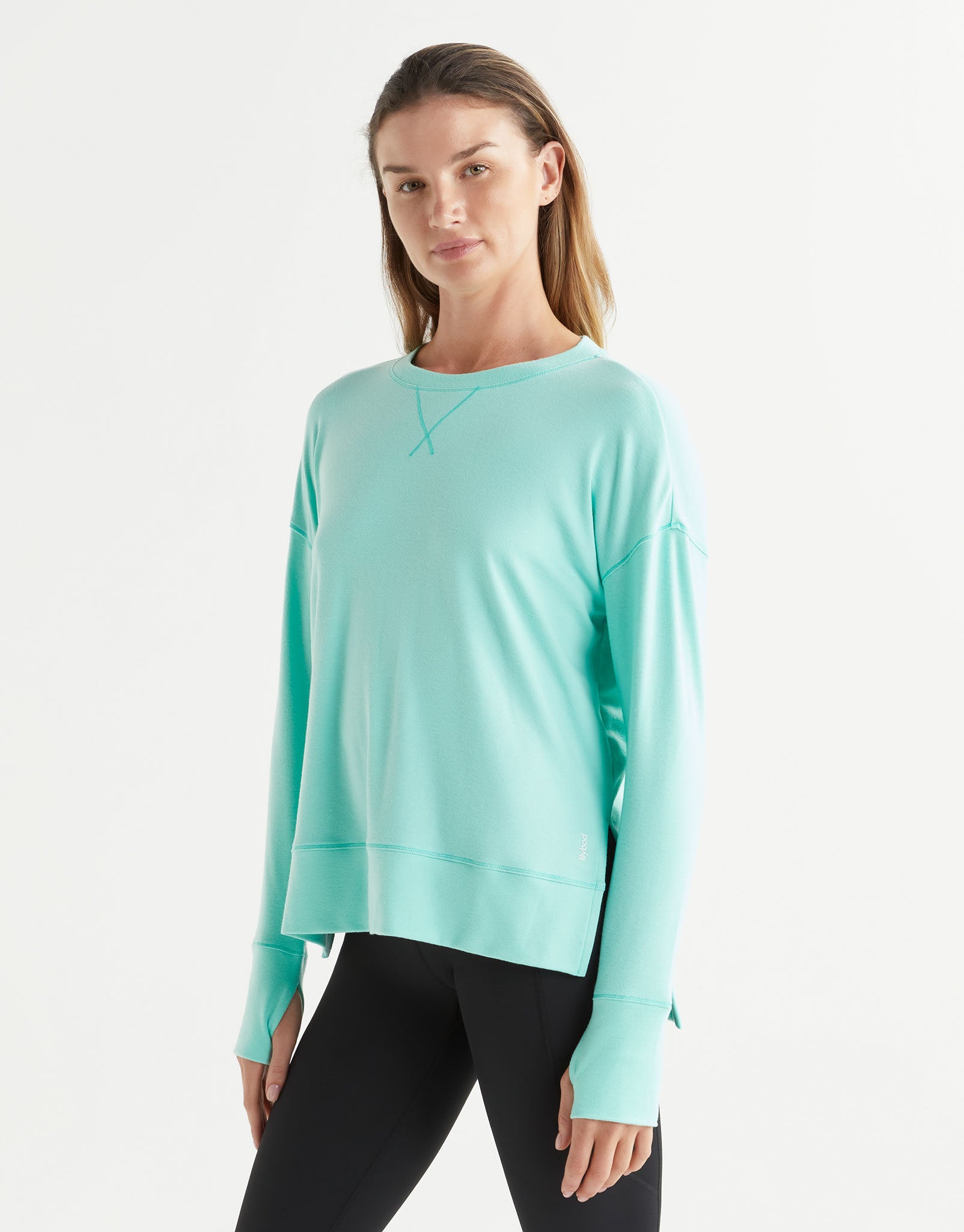 Woman wearing a light blue sweatshirt and black leggings on a white background
