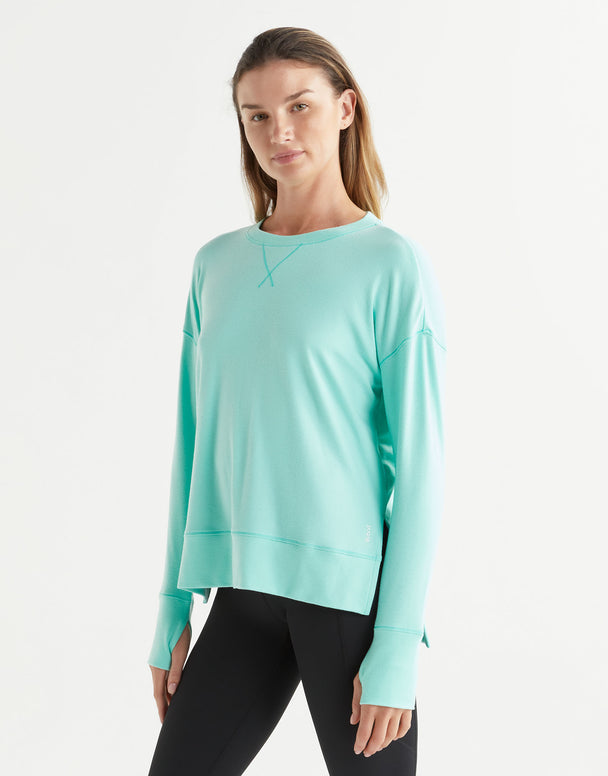 Woman wearing a light blue sweatshirt and black leggings on a white background