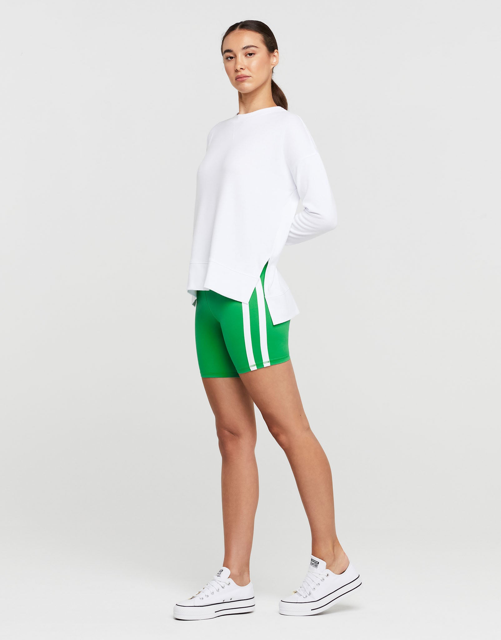 A woman wearing athletic shorts and a white long sleeved top