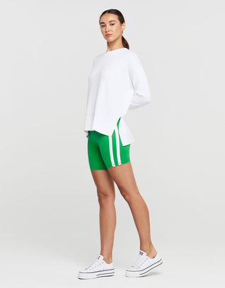 A woman wearing athletic shorts and a white long sleeved top