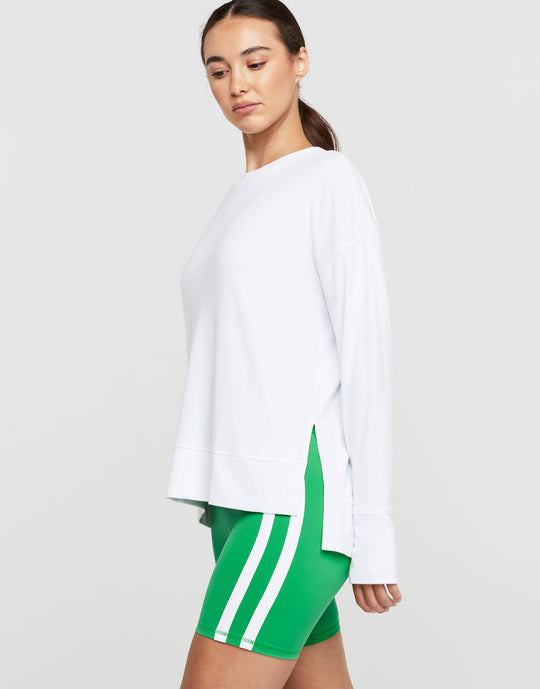 A woman wearing a white long sleeve top and green shorts