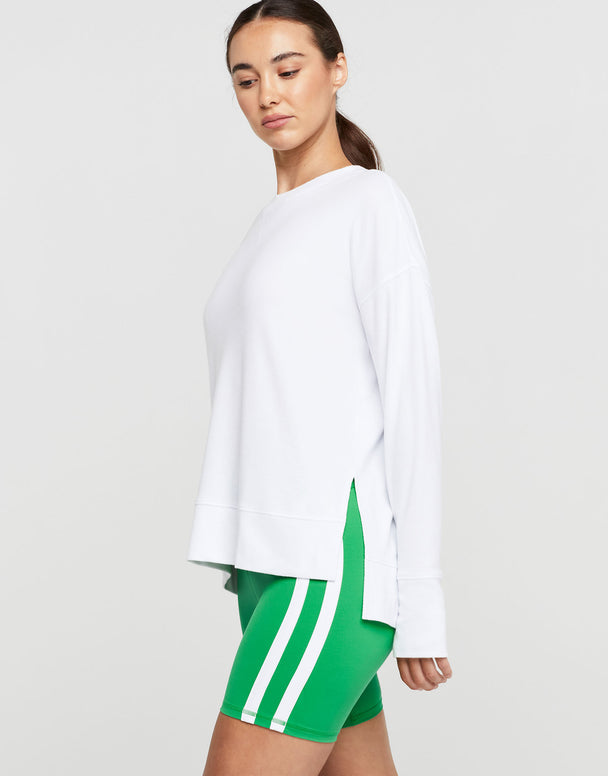 A woman wearing a white long sleeve top and green shorts