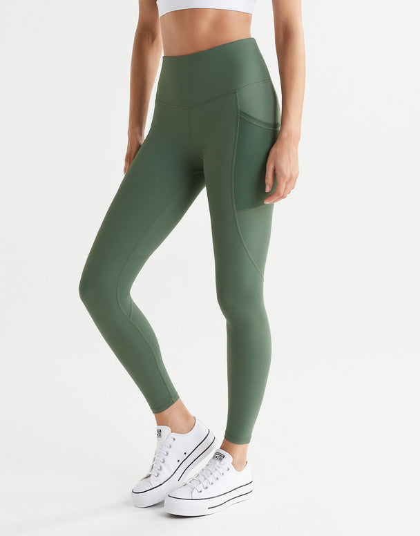 A woman wearing army green leggings and white runners