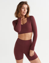 Woman wearing a maroon athletic outfit on a white background