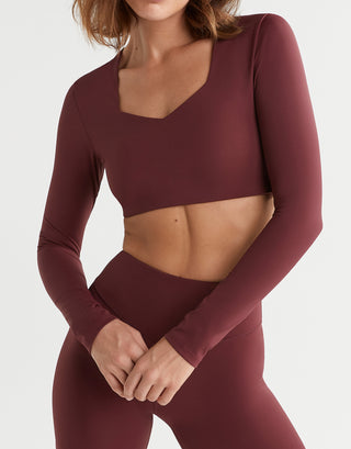 Maroon athletic outfit with long-sleeve top and leggings on a plain background