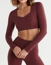 Maroon athletic outfit with long-sleeve top and leggings on a plain background