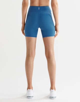 Woman wearing blue bike shorts and white sneakers from the back