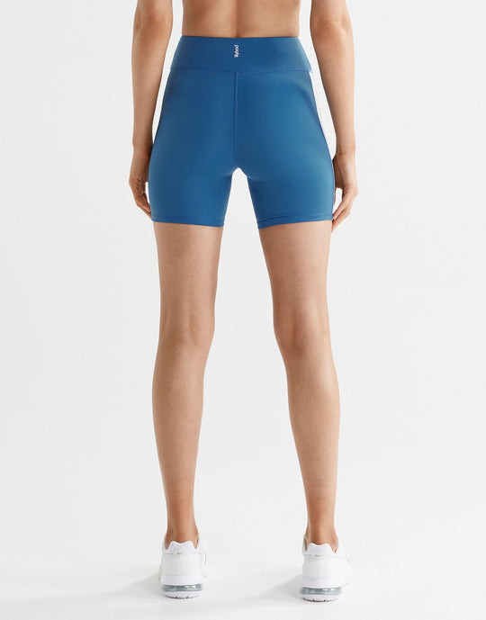 Woman wearing blue bike shorts and white sneakers from the back
